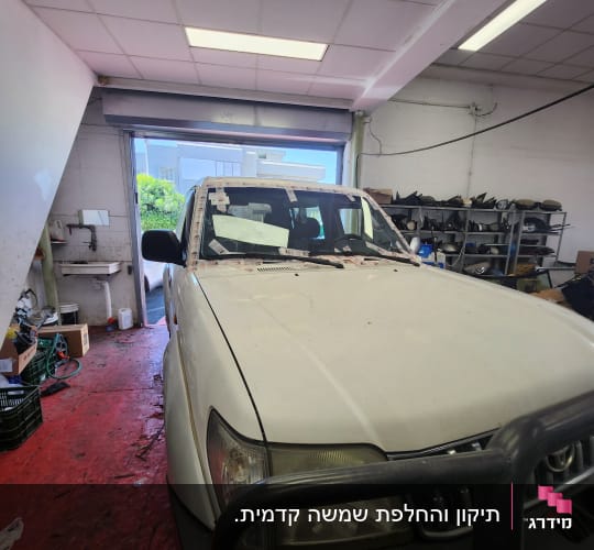 רכב לבן עם זכוכית קדמית בתהליך תיקון
